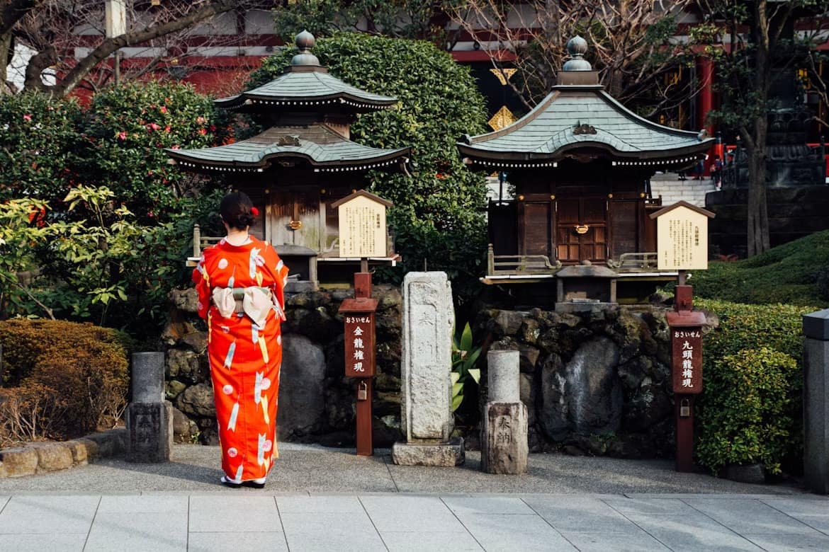 Femme en kimono devant deux petits pavillons japonais